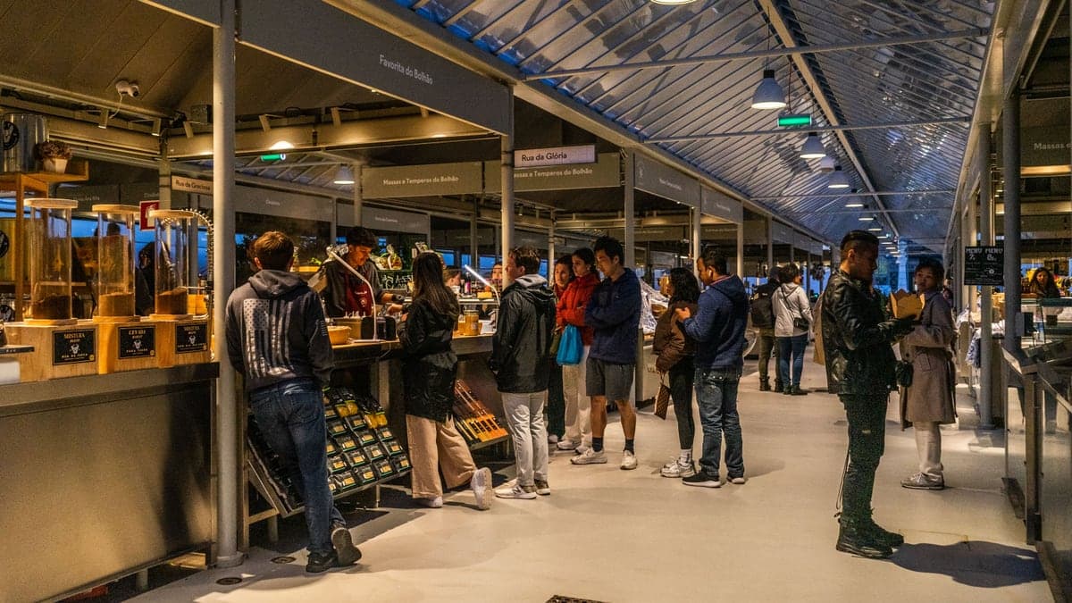 Visitors browse food stalls in a market hall in Porto, Portugal.